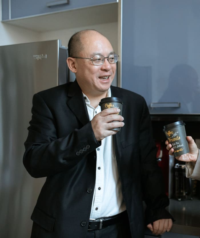 A consultant in a blazer holding a coffee, mid conversation