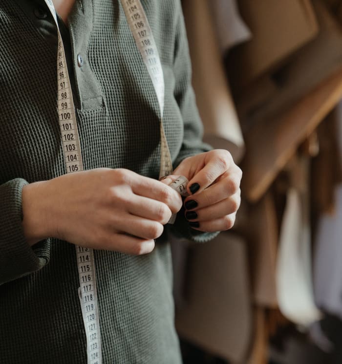 A tailor measuring a jacket with a tape measure