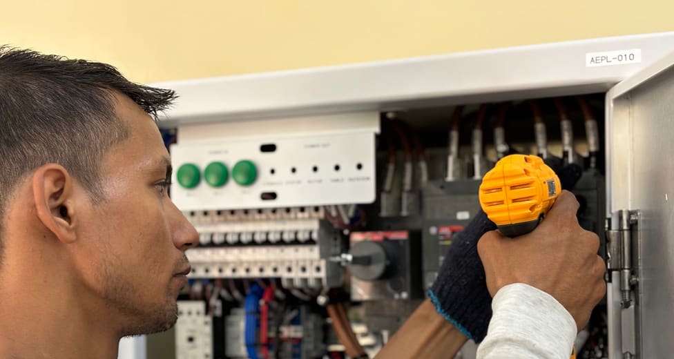An electrician working inside an open distribution board